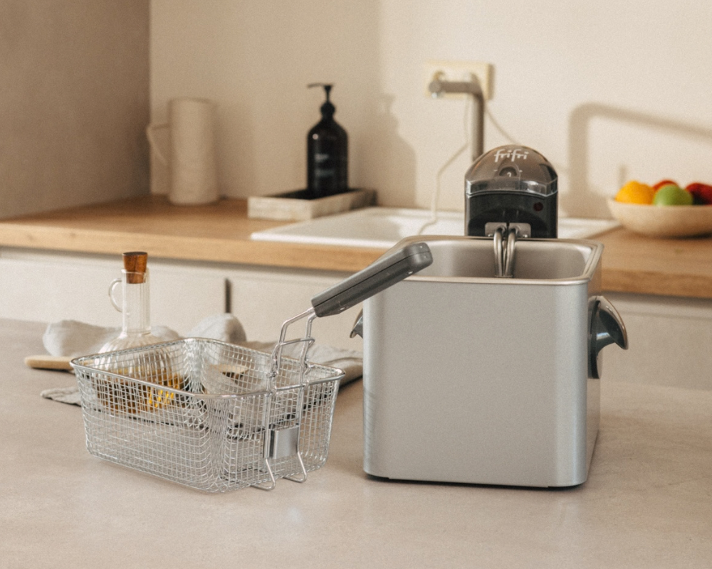 Une friteuse Frifri dont le panier en fil métallique a été retiré et posé sur un plan de travail.
