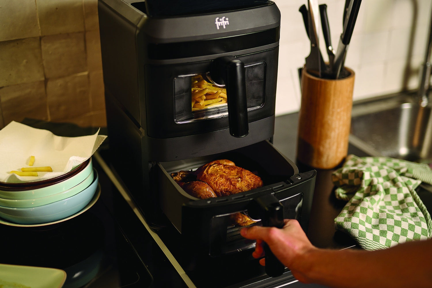 Zwarte airfryer met friet en geroosterde kip.