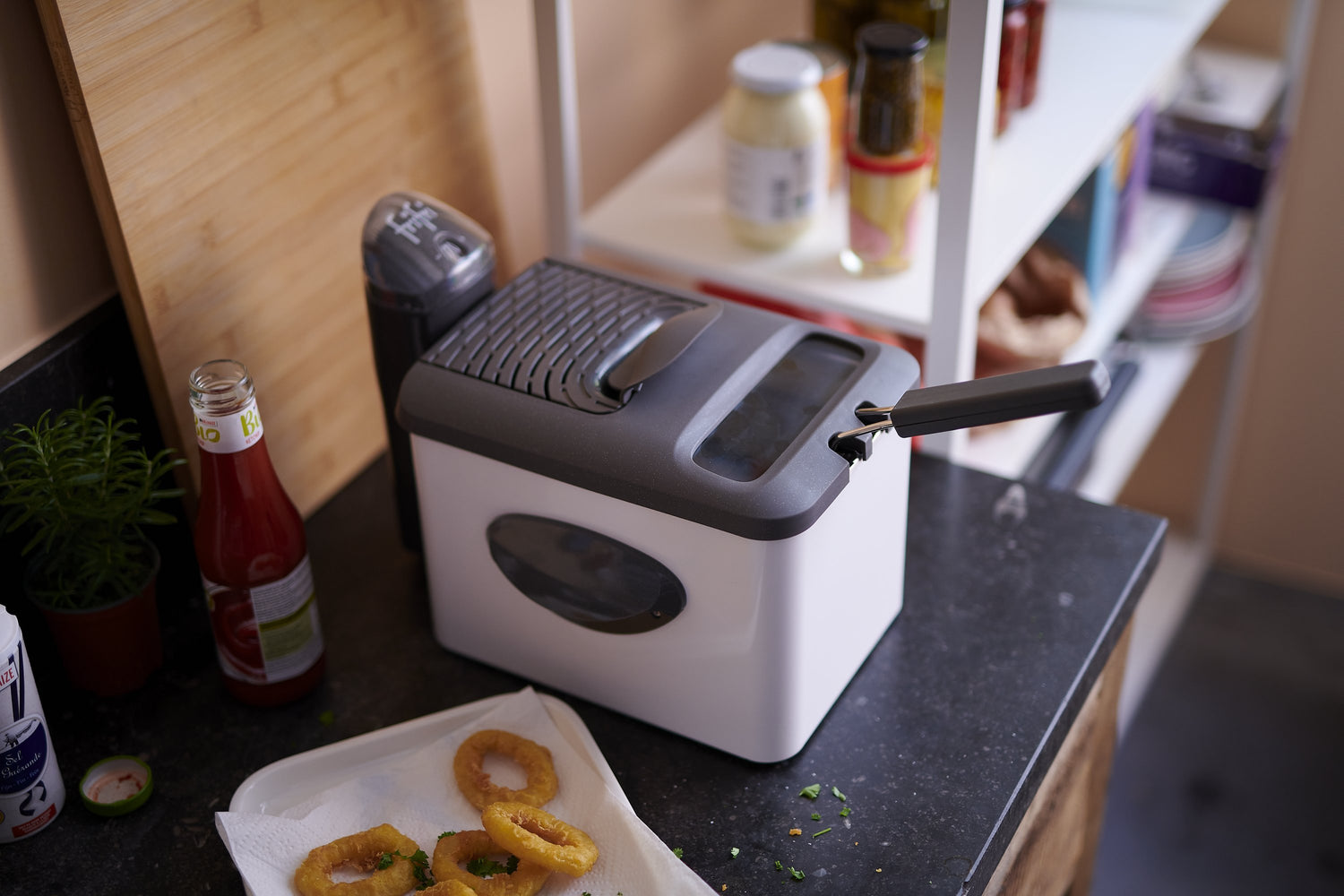 Witte en grijze friteuse op een zwart aanrecht.
