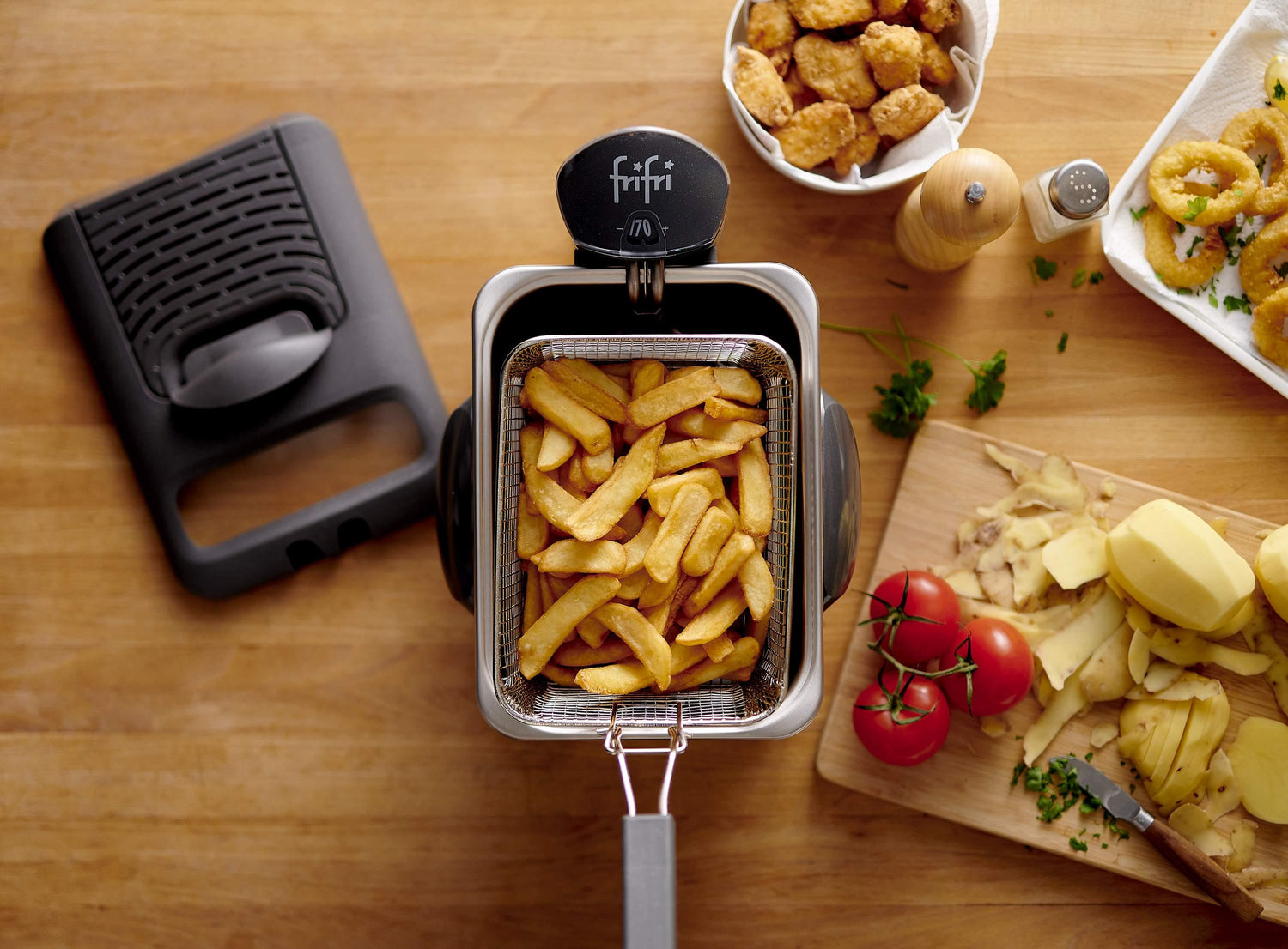 Une personne fait frire des snacks panés dans une friteuse sur un comptoir de cuisine, avec des bouteilles de bière et un bol contenant des snacks frits à proximité.