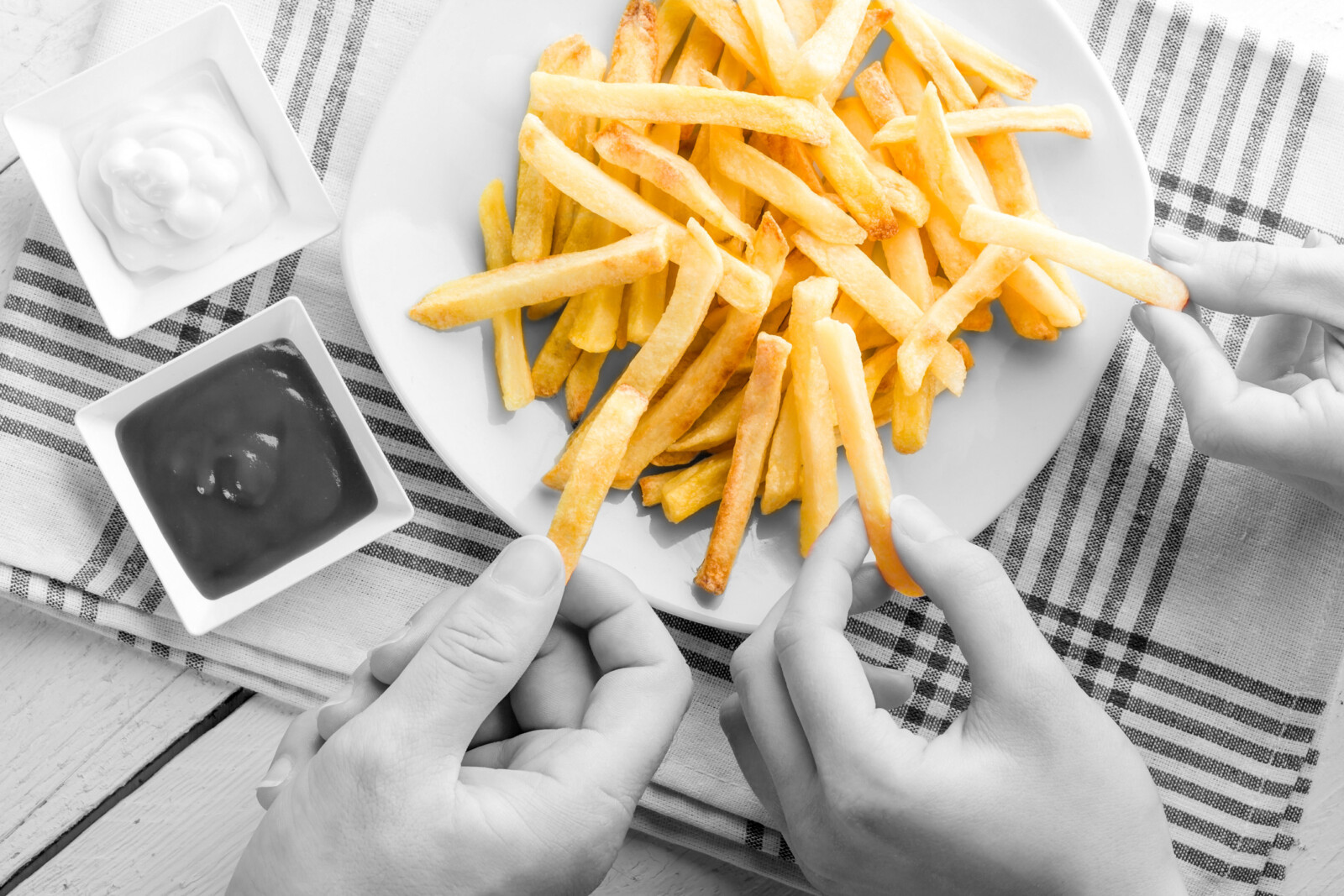 Three Hands Picking French Fries with Ketchup and Mayonnaise